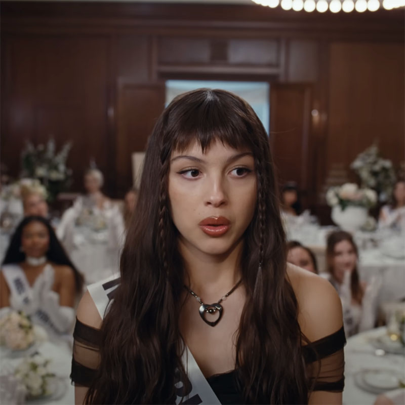Olivia Rodrigo in the "Obsessed" music video. Her long hair sports two long, thin braids.