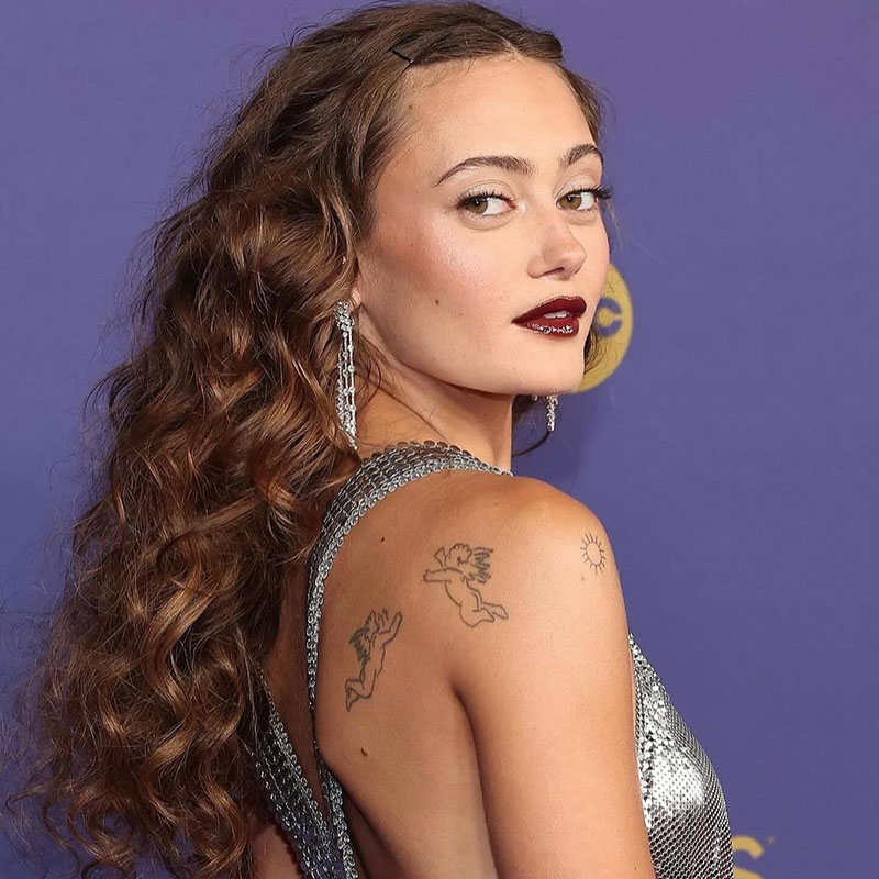 Ella Purnell at the 2024 Emmys. She is sporting crimson hair and curly hair.