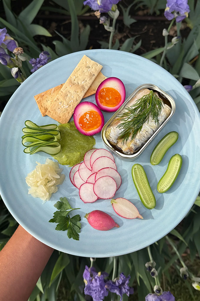 platter with tinned fish, eggs, crackers and greens
