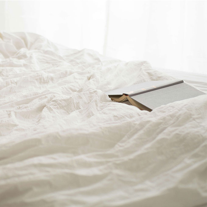 Black and Beige Book on White Bed Sheet