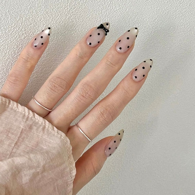 polka dot nails with a pearlescent base and black bow charm