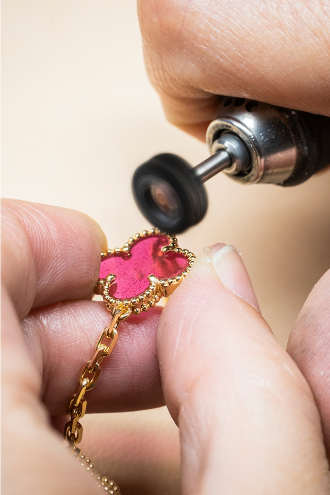 Pink enamel four leaf clover being polished carefully 
